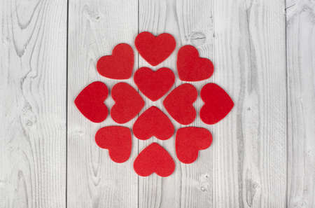 red hearts forming a geometric figure in the center of a white and gray wooden background. concept...
