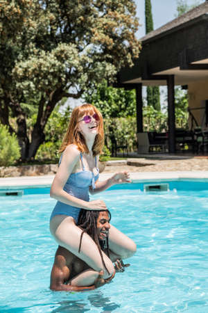 African-American man and white woman playing in a pool.