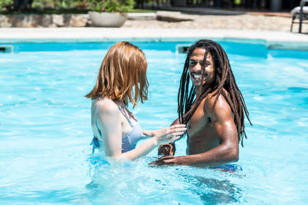 African-American man and white woman playing in a pool.