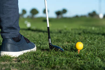 close-up of shoes, golf club, and golf ball on a driving range