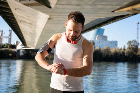 young athlete preparing his watch to start a sports activityの写真素材
