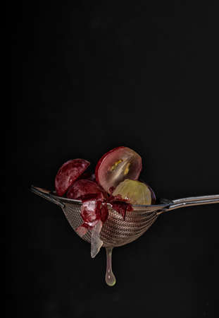 straining grapes with a silver metal strainer and making juiceの写真素材