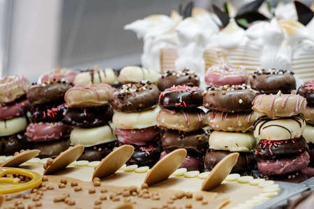 mountain of small doughnuts decorated differently in an ice-cream display caseの写真素材