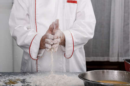Close-up of hands sprinkling flour on a blue wooden tableの写真素材