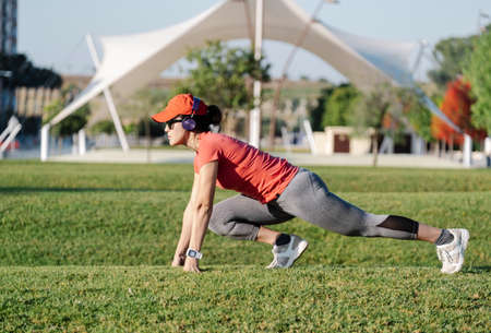 woman doing stretching exercises while listening to music in a parkの写真素材