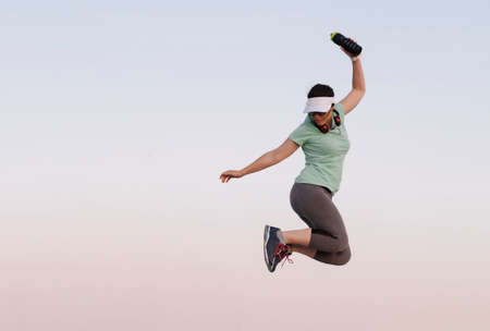 woman jumping while doing sport on a blue backgroundの写真素材