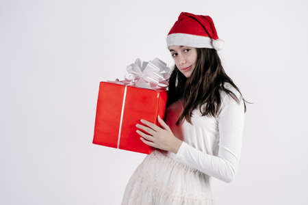 little girl with a Santa Claus hat holding a red gift on a white background. christmas concept.