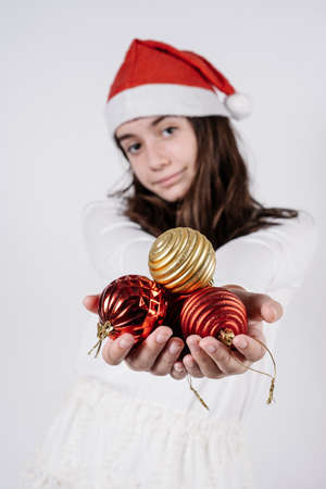 girl with a christmas hat holding christmas balls in her hands on a white background. christmas concept.の写真素材