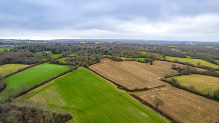 Aerial view of agricultural fields and forests in the countryside on a cloudy day.の写真素材