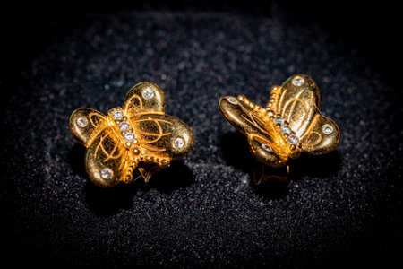 golden earrings on a black background close-up macro photoの写真素材