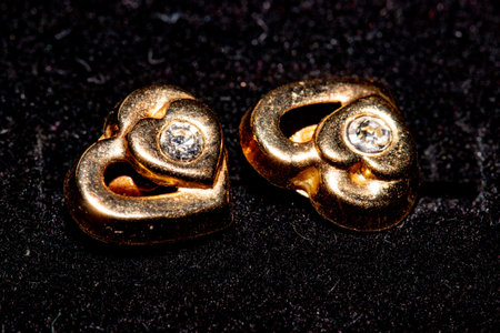 Two gold earrings on a black background. Close-up.の写真素材