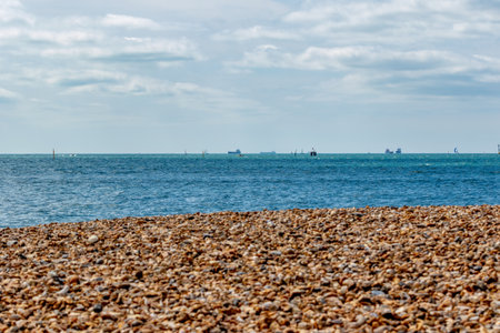 Seascape with pebble beach, blue sky and sailing boatsの写真素材
