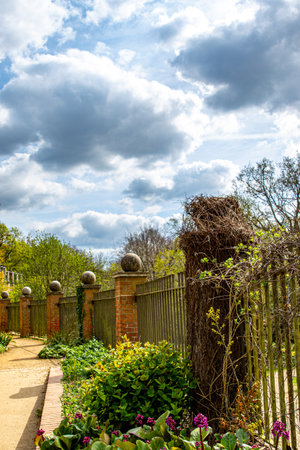 Garden with fence and flowers under cloudy sky, England, UKの写真素材