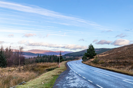 Road in the Scottish Highlands, UK. The road is surrounded by hills.