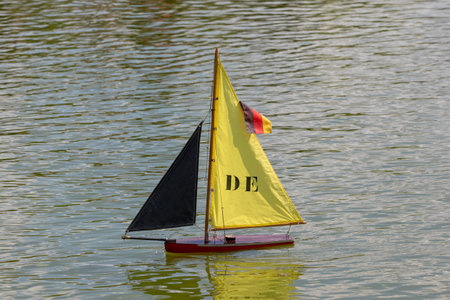 A small sailboat with a yellow sail floats on the water.の写真素材