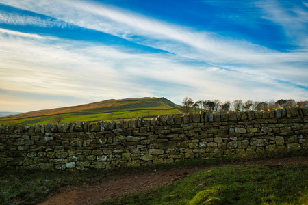 Beautiful landscape image of a stone wall on a hillside under a blue cloudy sky