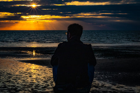Silhouette of a man looking at the sunset over the seaの写真素材