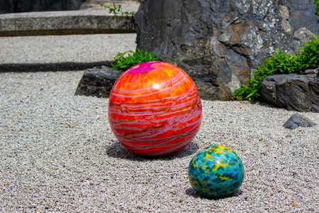 Colourful stone balls on the sand in the tropical garden.