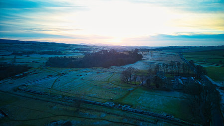 Aerial view of the sun setting over the countryside in winter.