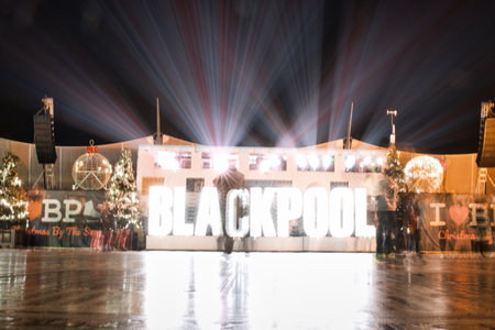 Illuminated Blackpool sign with light rays at night, reflecting on wet surface, with blurred motion effect.の写真素材