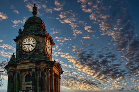 Historic clock tower silhouette against a dramatic sunset sky with scattered clouds in Lancaster.の写真素材