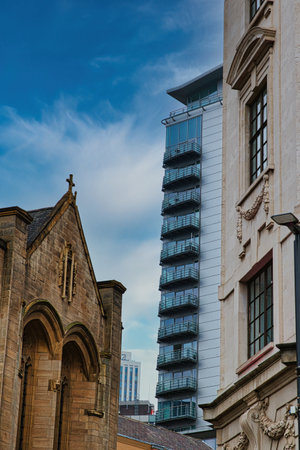 Contrast of old and new architecture with a historic church in the foreground and a modern...