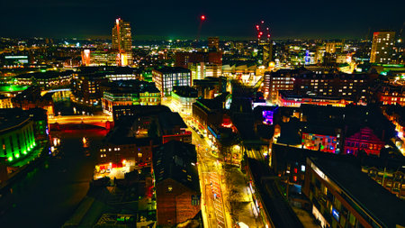 Panoramic night view of a bustling cityscape with illuminated streets and skyscrapers in Leeds, UK.