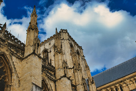 Majestic gothic cathedral facade against a dramatic sky with fluffy clouds, showcasing intricate...