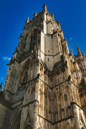 Gothic cathedral facade with intricate architecture against a clear blue sky, showcasing historical religious building's exterior details in York, North Yorkshire, England.の写真素材