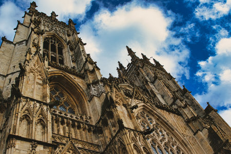 Dramatic angle of a Gothic cathedral's facade with intricate stone carvings against a vivid blue sky...