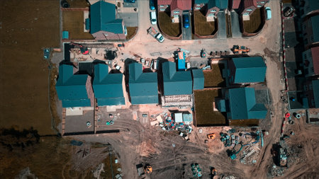 Aerial view of a residential construction site with multiple houses in various stages of completion. Construction materials and vehicles are visible around the site.の写真素材