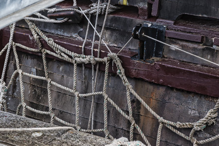 Close-up of ropes and rigging on an old wooden ship, showcasing the intricate knotwork and weathered...