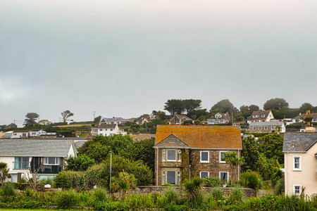 A scenic view of a coastal village with various houses, including a stone house with an orange roof,...