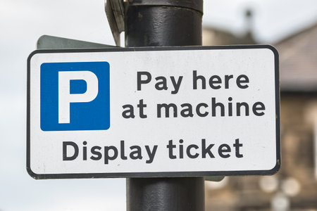 A parking sign indicating payment instructions. It reads 'Pay here at machine' and 'Display ticket' with a blue 'P' symbol for parking.の写真素材