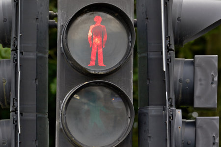 A close-up of a traffic light displaying a red pedestrian signal, indicating that pedestrians should...