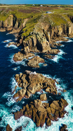 Aerial view of rugged coastal cliffs with rocky formations and crashing waves. The landscape...