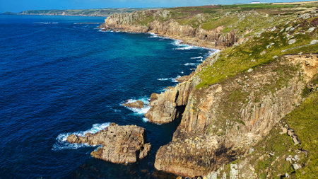 A stunning coastal view featuring rugged cliffs and clear blue waters. The landscape showcases a mix...