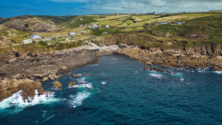 A scenic coastal view featuring rocky shores, clear blue waters, and green hills in the background....