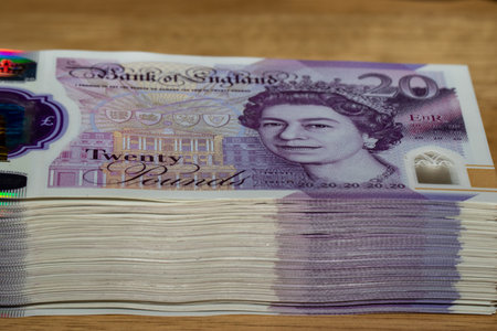 A stack of twenty pound banknotes from the Bank of England, featuring Queen Elizabeth II and the words Twenty Pounds.の写真素材