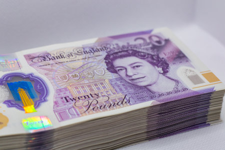 A stack of twenty-pound banknotes from the Bank of England, featuring a portrait of Queen Elizabeth II. The notes are colorful with holographic elements, showcasing the currency's design and security features.の写真素材