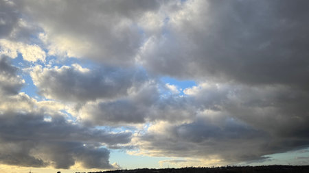 A wide shot of a mostly cloudy sky, predominantly gray and dark gray clouds with some lighter,...