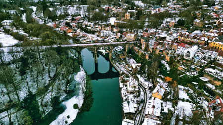 Aerial view of a snow-covered town with a railway viaduct spanning a river.  Houses cluster on a hillside, contrasting with the green river and snow-dusted trees in Knaresborough, UK.の写真素材
