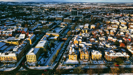 Aerial view of a snow-covered town, showcasing residential buildings, roads, and a railway line.  Buildings are primarily low-rise, with varied architectural styles in Harrogate, UK.の写真素材