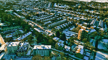 Aerial view of a snow-covered residential area, featuring houses, streets, and green spaces.  Multi-story buildings and varied architectural styles are visible  in Harrogate, UK.の写真素材