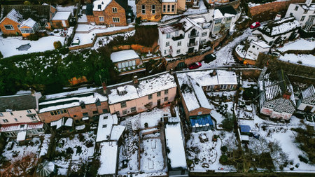 Aerial view of a snow-covered residential area, featuring multiple terraced houses, gardens, and vehicles.  Houses exhibit varying architectural styles and roof designs in Knaresborough, UK.の写真素材