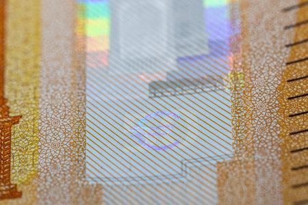Close-up of a banknote's security feature; shows a pale-blue euro symbol on a diagonally-striped...