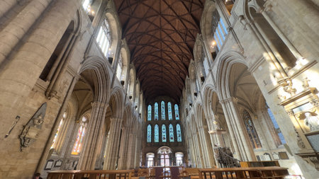 Interior view of a cathedral featuring high arched ceilings, stained glass windows, and stone columns in a symmetrical composition.の写真素材