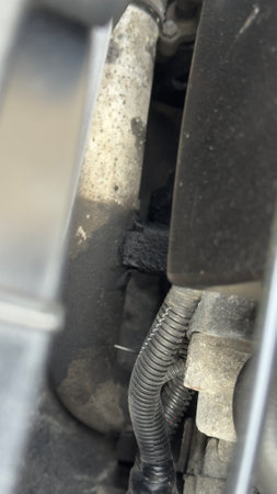 Close-up view of an engine compartment. It features hoses, wiring, and engine components, all with visible dirt and wear.の写真素材
