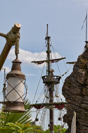 A view of a pirate ship mast with a lantern in the foreground against a partly cloudy sky.の写真素材