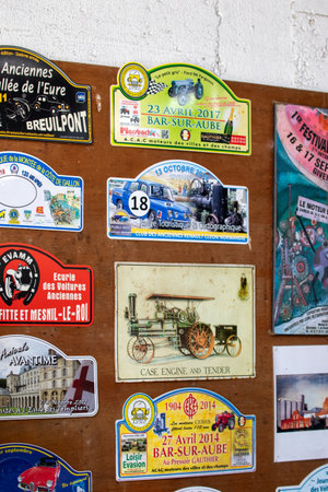 A collection of colorful automotive rally stickers and plaques affixed to a wooden surface. Dates range from the early 20th century to 2019 in Giverny, France.の写真素材